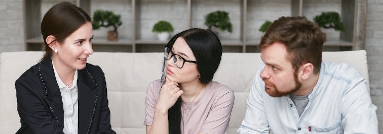 Three individuals engaged in conversation about workplace flexibility, comfortably seated on a couch.
