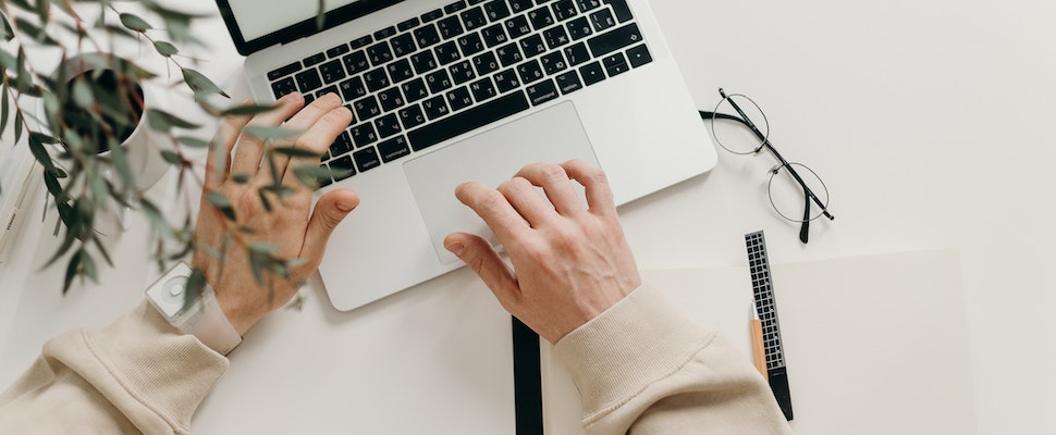 Person in Beige Long Sleeve Shirt Using Macbook Pro