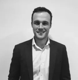 Smiling man in a suit against a plain background.