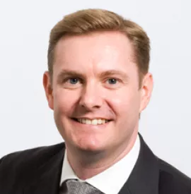 Smiling man in a suit with a white background.