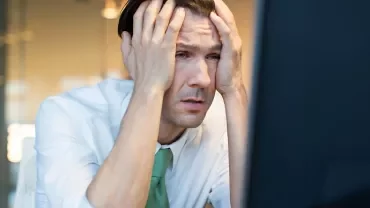 Man in office holding head in frustration