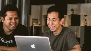 Two people smiling and looking at a laptop screen.
