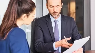 Two professionals reviewing a document in an office setting.