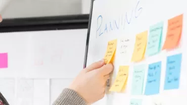 Man arranging colorful sticky notes on a whiteboard labeled 'Planning'.