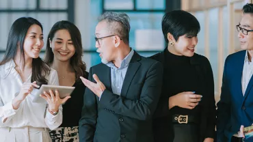 Group of five professionals discussing with a tablet in an office setting.