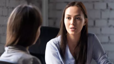 Two people engaged in a serious conversation in an office setting.