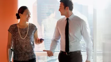 Two professionals walking and talking in a sunlit office