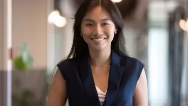 A woman smiling in an office hallway.
