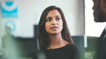 Woman speaking to a man in a business setting.