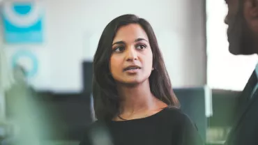 Woman speaking to a man in a business setting.