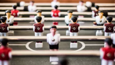 Close-up view of a foosball table with red and white player figures.