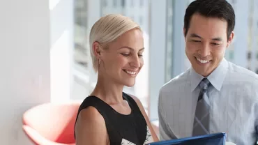 Two colleagues discussing documents in a bright office.