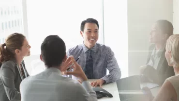 Business meeting with diverse team smiling around a conference table.