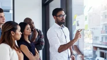 Team discussing charts on a window with sticky notes