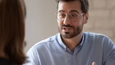 Man with glasses having a conversation with a woman.