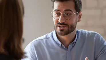 Man with glasses having a conversation with a woman.