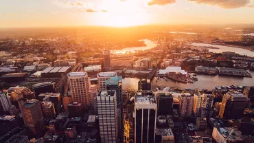 Aerial view of a cityscape with buildings and a river at sunset.