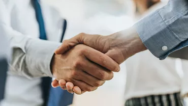 Two people in business attire shaking hands in a close-up view.