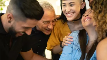 Group of diverse people smiling and hugging each other closely.