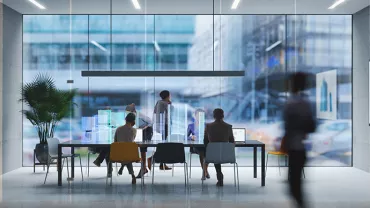 People in a modern office with glass walls during a meeting.