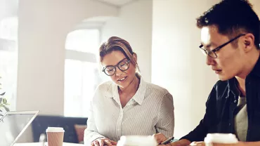 Two people collaborating over coffee in a bright office setting.
