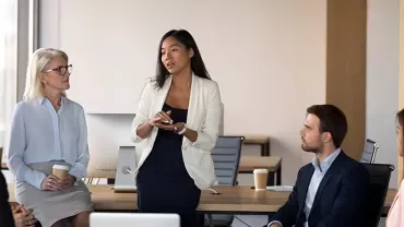 Businesswoman leading a discussion with colleagues in a modern office.