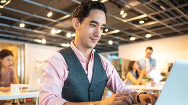 Man at laptop in modern office setting.