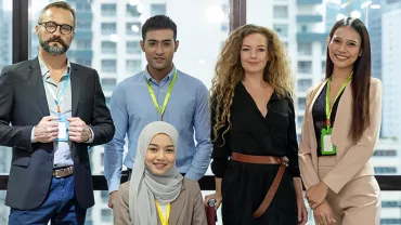 A diverse group of five people smiling in a modern office setting.