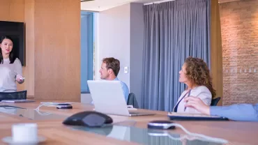 A woman giving a presentation to colleagues in a meeting room.