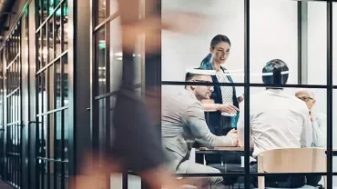 People in a glass-walled conference room having a meeting.