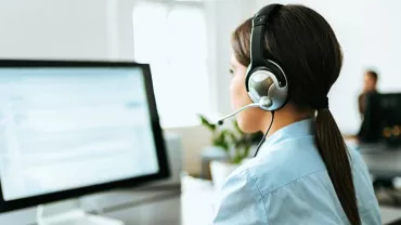 Person in a headset working at a computer in an office.