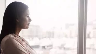 A woman gazing thoughtfully out of a window.
