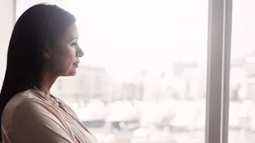 A woman gazing thoughtfully out of a window.