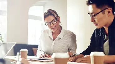 Two people discussing notes in a coffee shop.