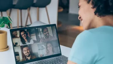 Person in a blue shirt on a video call with four people on their laptop.