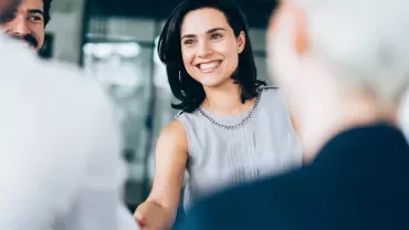 Smiling woman shaking hands in a group meeting.