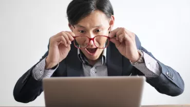 Excited man looking at laptop screen with surprise.