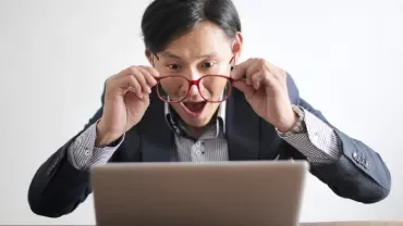Excited man looking at laptop screen with surprise.
