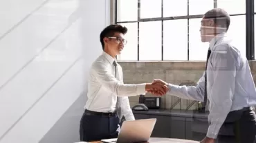 Two men shaking hands in an office setting.