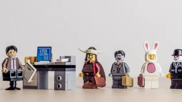 Lego minifigures in costume line up in an office setting.