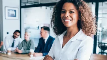 Confident woman in a white shirt smiling at a business meeting.