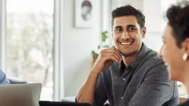 Group of four people smiling during a meeting.