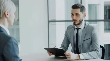 Professional recruiter interviewing a candidate in a modern office setting, representing effective recruitment strategies for attracting IT and tech talent.