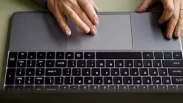 Individual engaged in typing on a laptop, with fingers on the keyboard.