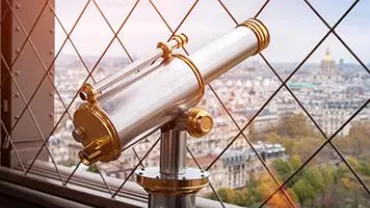 Telescope overlooking city view through lattice fence.
