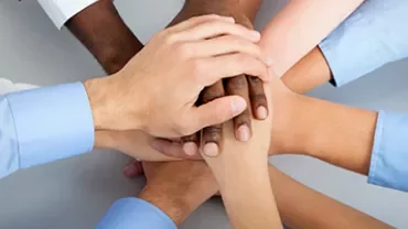 Diverse group of hands stacked together in unity.