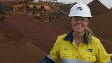 Person in safety gear smiling at a mining site
