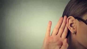 Person cupping hand to ear, listening intently.