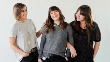 Three women smiling and laughing together.