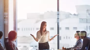 Businesswoman giving a presentation to colleagues in a meeting room.